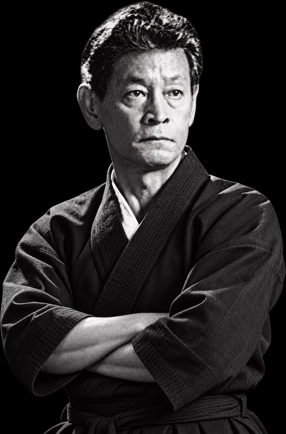Retrato do mestre Osamu Ozawa, fundador da TKIC, com uniforme de karatê e braços cruzados